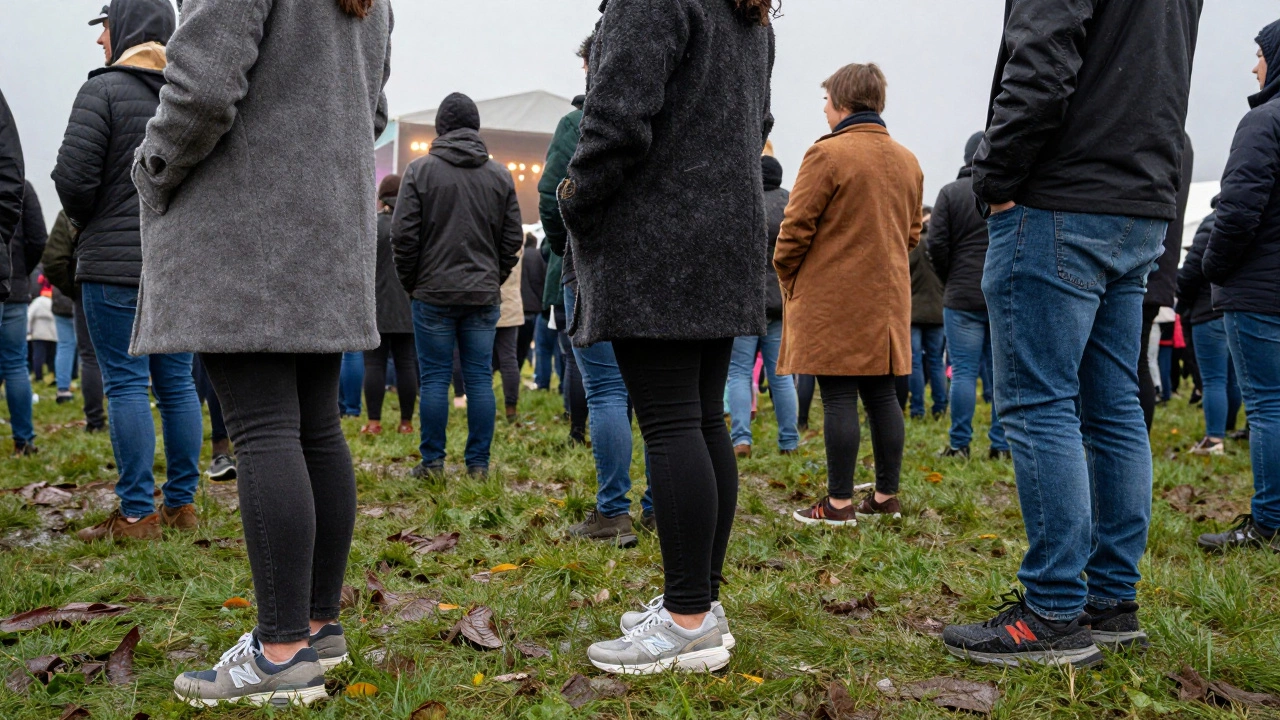 Festival-goers in muddy grass wearing waterproof trainers under misty skies